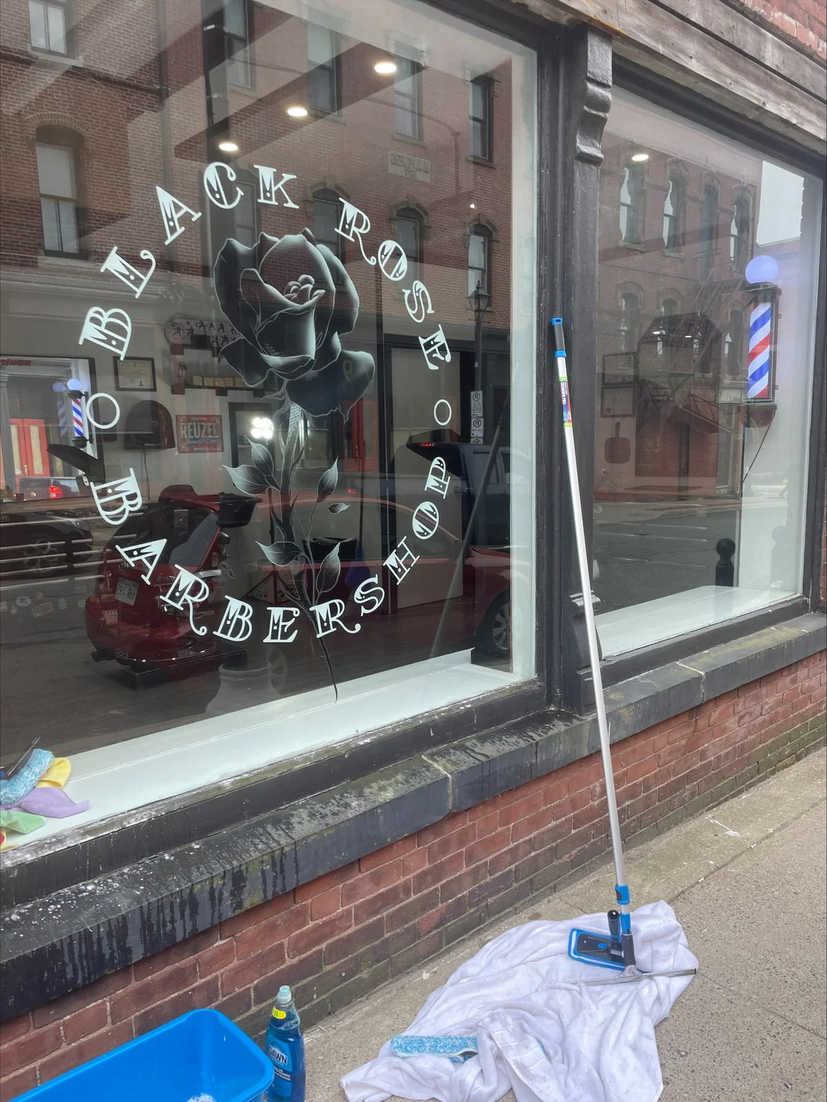 Window cleaning at a local barbershop, showing the shop windows and cleaning equipment